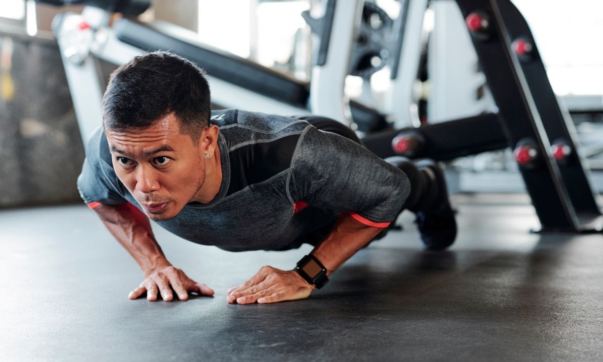 get fit without machines - asian man doing diamond push-ups in gym during