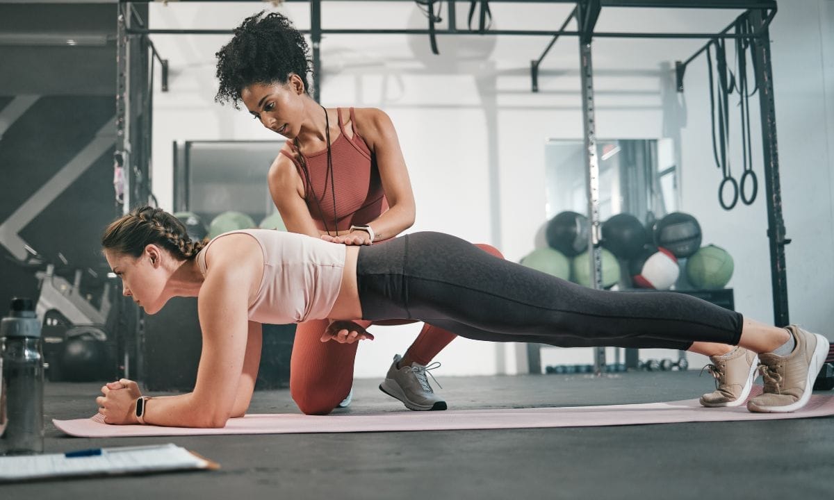 personal trainer at gym with woman for training
